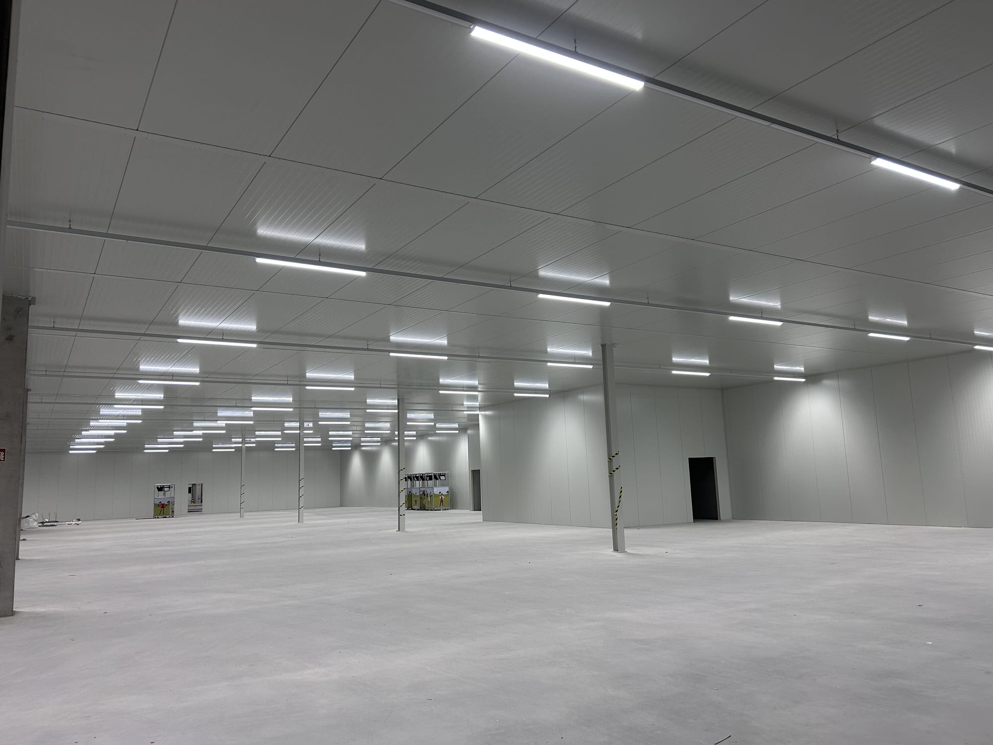 Completed white sandwich-panel warehouse interior with linear lighting